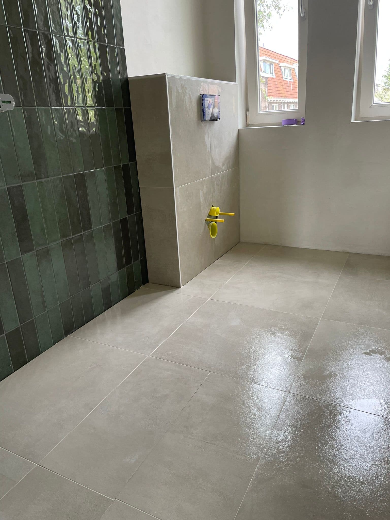 Badkamer met verticaal gelegde groene glanstegels en grootformaat betonlook vloer, Kemp Tegelwerk Heemstede