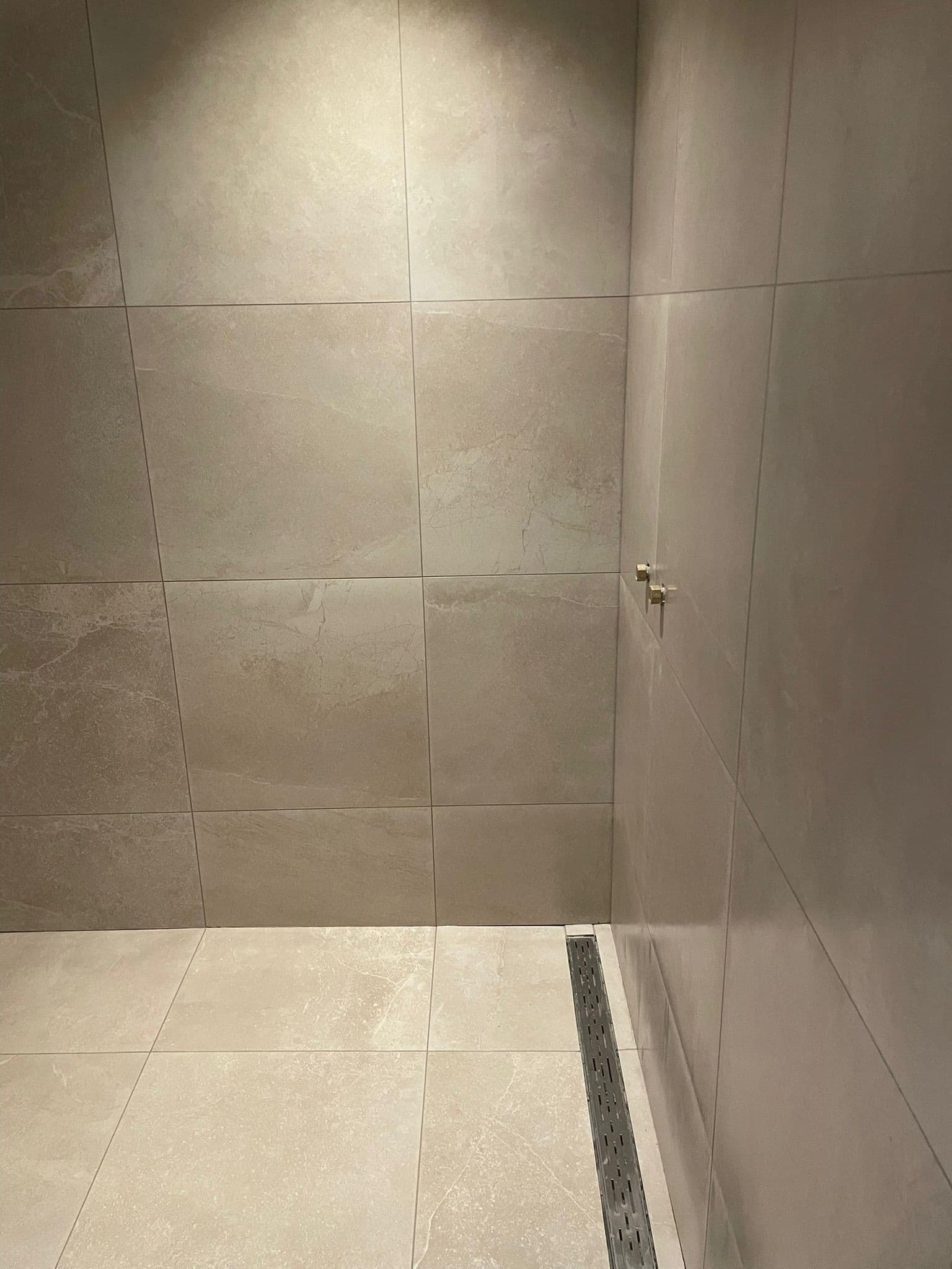 Strakke inloopdouche met grootformaat zandsteenlook tegels en rvs douchegoot, Kemp Tegelwerk Bloemendaal